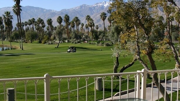 Un parcours de golf offrant une vue sur les montagnes et les palmiers.