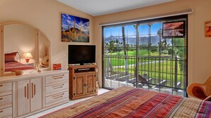 Une chambre dotée d’une grande fenêtre donnant sur un terrain de golf et des montagnes.
