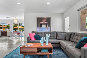 A modern living room with a sectional sofa, a coffee table, and a framed artwork on the wall.