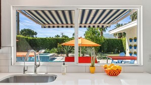 Cozinha com vista para uma piscina, móveis de exterior e plantas em vasos.