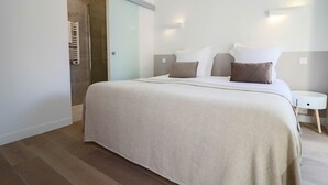 A modern bedroom with a large bed, a bedside table, and a glass shower door. - Apt luxe 1min Palais Festivals (Cannes)