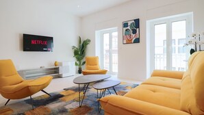A modern living room with yellow furniture, a flat-screen TV displaying 'NETFLIX', and a large window with a view. - Apt luxe 1min Palais Festivals (Cannes)