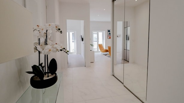 A modern hallway with a glass partition, white walls, and a potted orchid plant. - Apt luxe 1min Palais Festivals (Cannes)