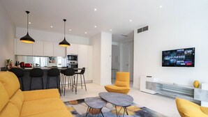 A modern living room with a sofa, two armchairs, a coffee table, and a TV mounted on the wall. - Apt luxe 1min Palais Festivals (Cannes)