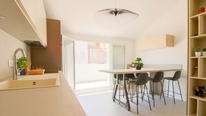 A modern kitchen with a white countertop, a sink, and a dining area with a table and four chairs. There is a ceiling light fixture above the table. - Rooftop design apartment Cannes (Cannes)