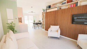 A modern living room with a sofa, a white armchair, and a wooden accent wall. There is a bookshelf with books and a sign on the wall. - Rooftop design apartment Cannes (Cannes)