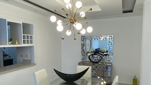 Un comedor moderno con una mesa de vidrio, sillas blancas y una lámpara de techo original.