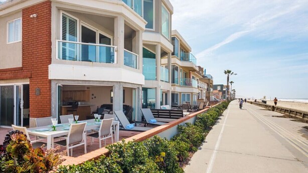 A multi-story hotel with balconies, outdoor seating, and a beach view. - Ocean Front Beach Get Away w/ AC! (San Diego)