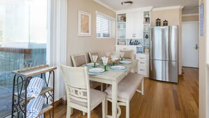 A dining area with a table set for four, a refrigerator, and a view of the outside. - Ocean Front Beach Get Away w/ AC! (San Diego)