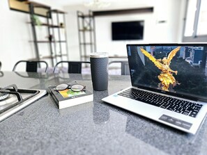 Una computadora portátil mostrando una estatua dorada, un vaso y un par de gafas sobre una mesa.