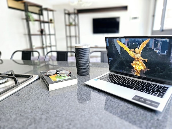 A laptop displaying a golden statue, a tumbler, and a pair of glasses on a table.