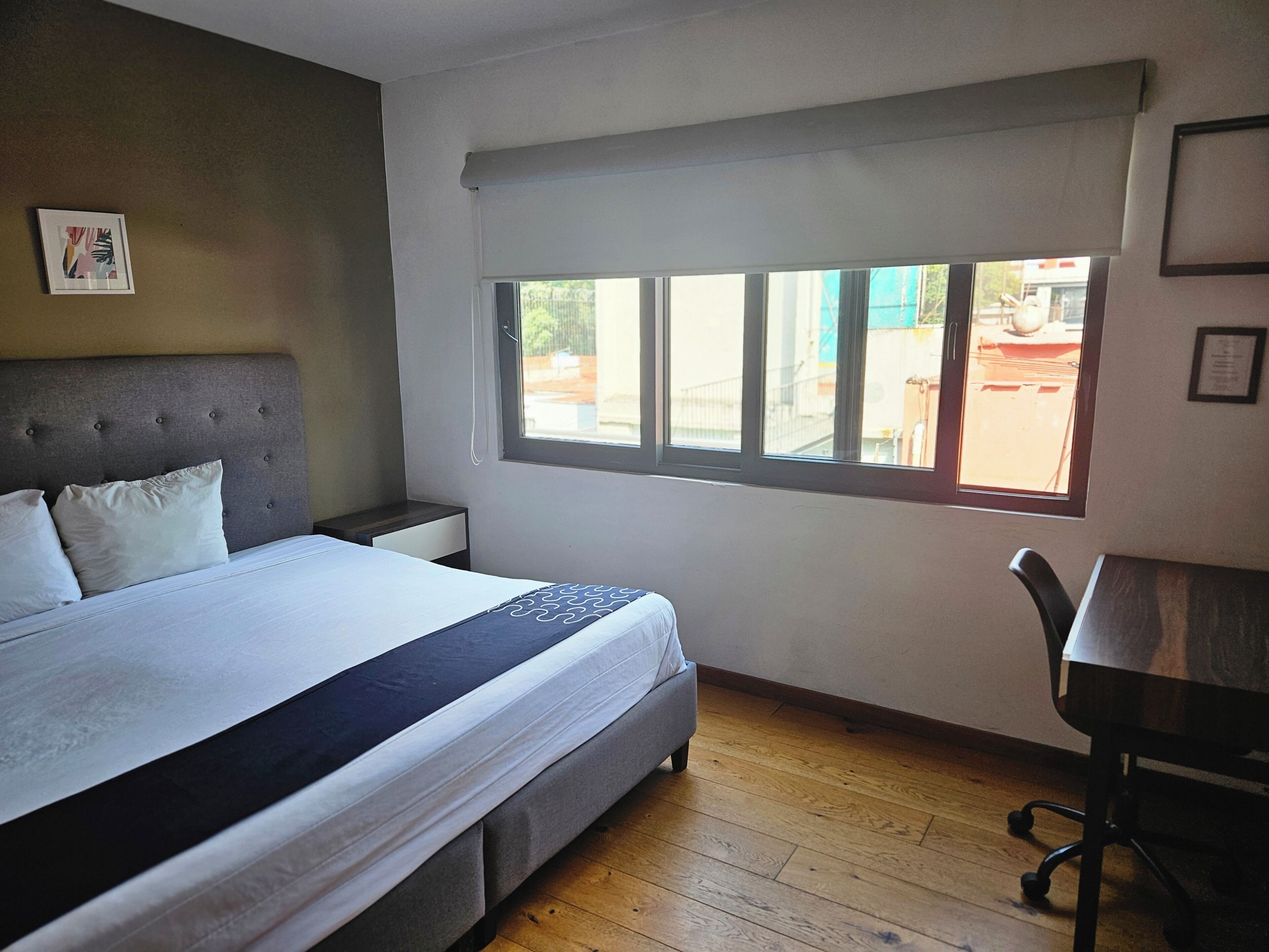 A bedroom with a bed, a desk, and a window.
