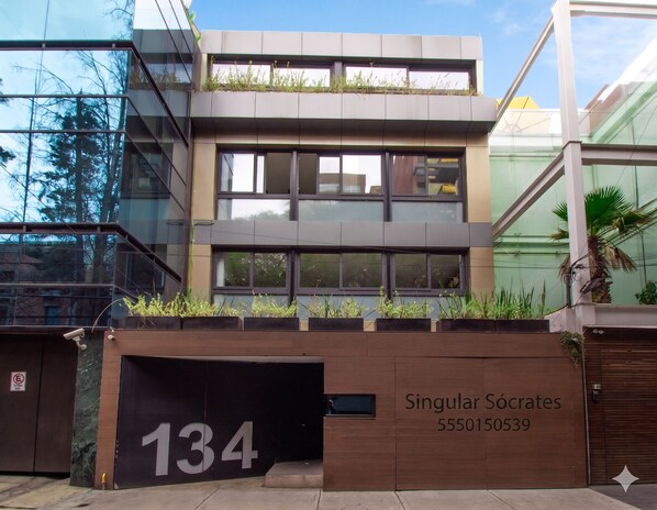 A modern building with a large number '134' on the facade, a contact number, and a name 'Singular Sócrates' below it.