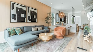 A modern living room with a sectional sofa, a round coffee table, and a dining area in the background. - Atlanta Rooftop Retreat Sleeps 10 + Parking (Atlanta)