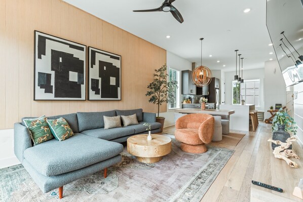 Una sala de estar moderna con un sofá modular, una mesa de centro redonda y un comedor al fondo.