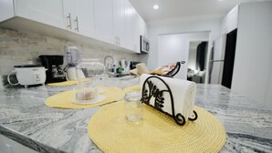 A kitchen with white cabinets, a microwave, a coffee maker, and a woven placemat on the counter.
