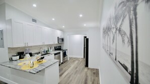 A modern kitchen with white cabinets, a granite countertop, and a microwave.