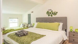 Un dormitori amb un llit, una taula de nit, una làmpada i una decoració a la paret.