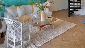 A modern living room with a white sofa, a coffee table, and a black spiral staircase. - SEArider ONE at Turtle Bay (2 bedroom / 2 bath) (Kahuku)