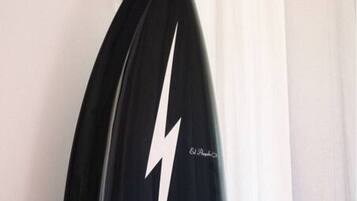 Una tabla de surf apoyada contra una pared en una habitación con una cortina blanca.