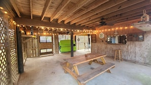 Un interior rústico de madera con banca y mesa, luces de cuerda y un sofá verde.