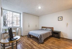 Cozy retreat with a bed, desk, and wardrobe, offering a view of the outside.