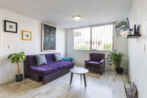 Cozy living space with a sofa, armchair, and flat-screen TV.