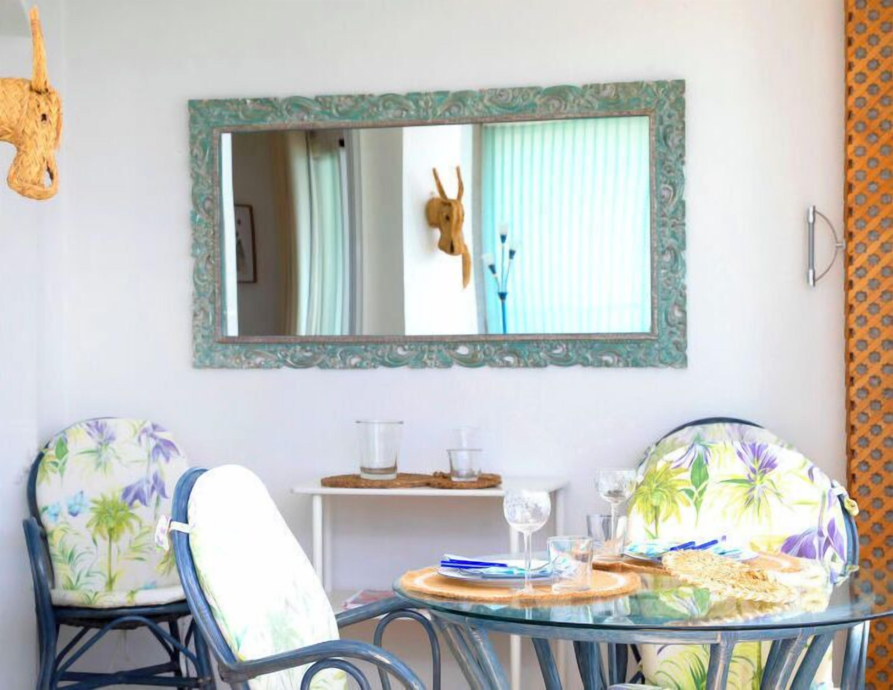 A dining area with two chairs, a table, and a mirror on the wall.