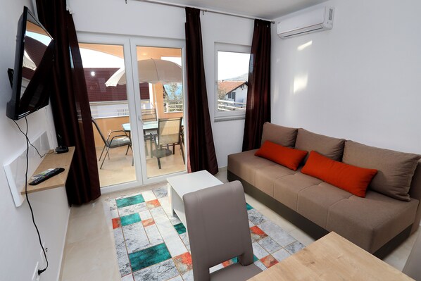A living room with a sofa, a TV, a table, and a chair.