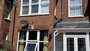 A brick building with multiple windows, some with shutters, and a satellite dish on the roof. - Seafront Sheringham 1 bed Apt sleeps 4 - 1xdog (SHERINGHAM)
