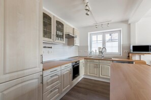 A modern kitchen with light wood cabinets, a stainless steel oven, and a built-in microwave. - House Sommerwind iii near the North Sea with Fireplace, Wi-Fi, Garden, Terrace & BBQ (Tating)