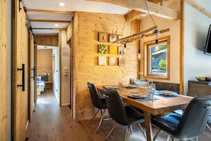 A wooden interior with a dining area, a bed, and a window.
