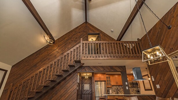 Eine moderne Küche mit Holzelementen, einem Essbereich und einer Treppe zu einer oberen Ebene.