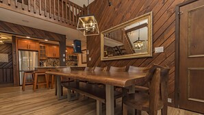 Ein Essbereich mit einem Holztisch und Stühlen, einem großen Spiegel an der Wand und einer Treppe im Hintergrund.