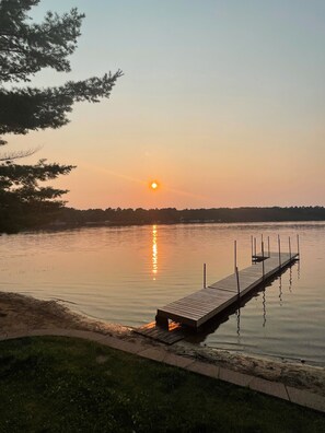 A wooden dock extending into calm water with a sunset in the background. - Peaceful Lakefront Home for Rent on Side Lake chain of lakes! (Side Lake)