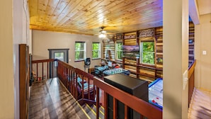 A wooden-floored room with a foosball table, a pool table, and a bar area with a sign that reads "GAMING". - Stylish and Cozy Retreat in Gatlinburg-Family and Pet Friendly-Quaint and Quiet (Gatlinburg)