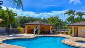 A swimming pool with a stone-tiled edge, a covered seating area, and lounge chairs. - Maui Banyan G202 - King Bed, Ocean View, Across from Kamaole Beach (Kihei)
