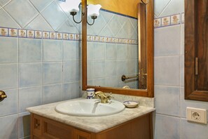 Une salle de bain équipée d’un lavabo, d’un miroir et d’un luminaire.