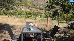 An outdoor table with two chairs, a lantern, and two cans on a gravel surface. - Country Cabin "Finca Nim 2" on a Farm with Mountain View, Pool & Wi-Fi (Mogán)