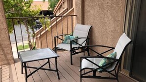 Una terraza de madera con dos sillas y una mesa.