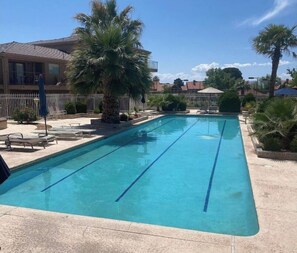 A rectangular swimming pool with clear blue water, surrounded by a tiled deck.