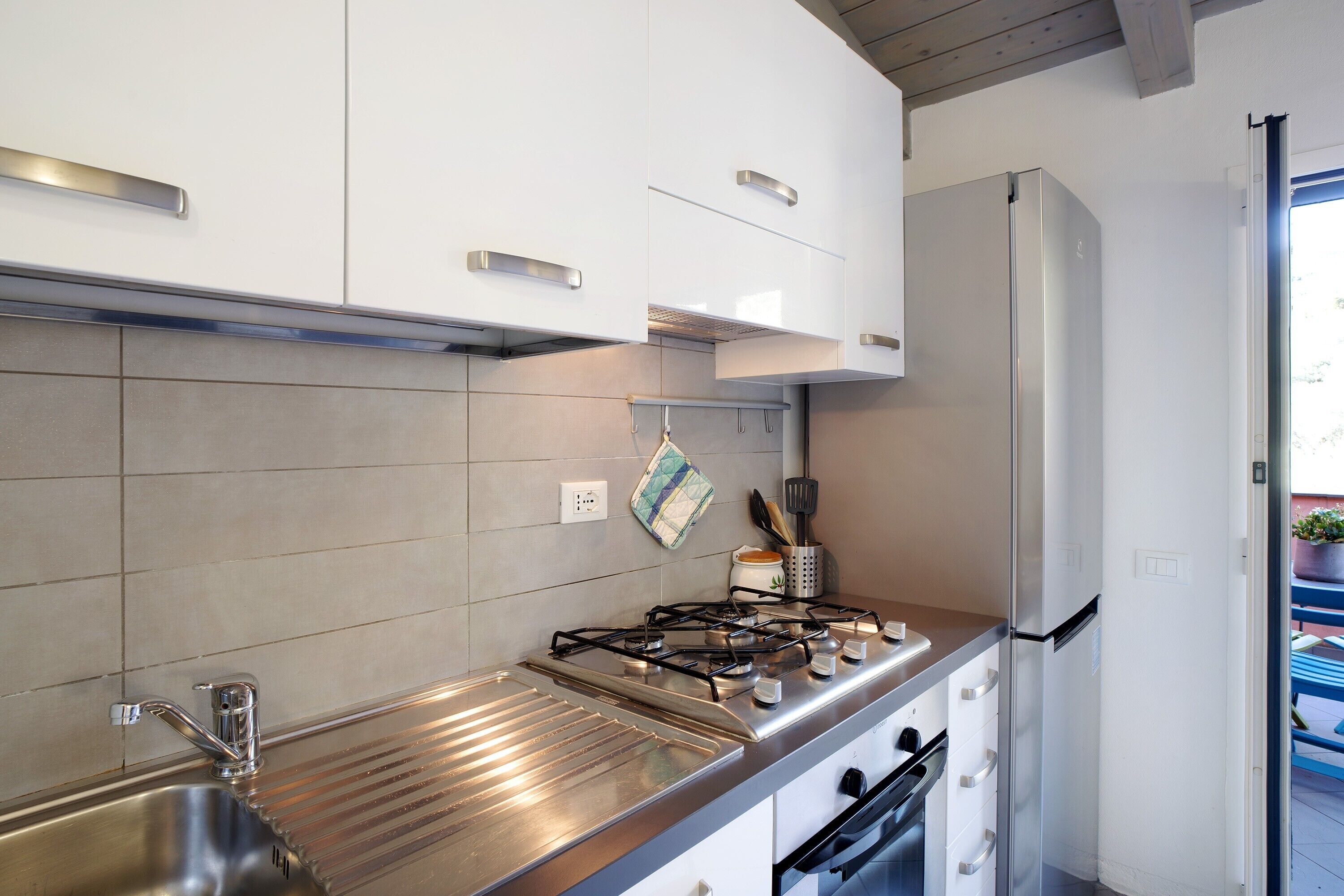 Una cocina moderna con electrodomésticos de acero inoxidable, armarios blancos y salpicadero de azulejos.