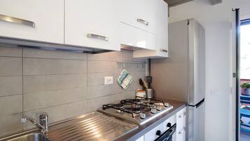 Una cocina moderna con electrodomésticos de acero inoxidable, armarios blancos y salpicadero de azulejos.