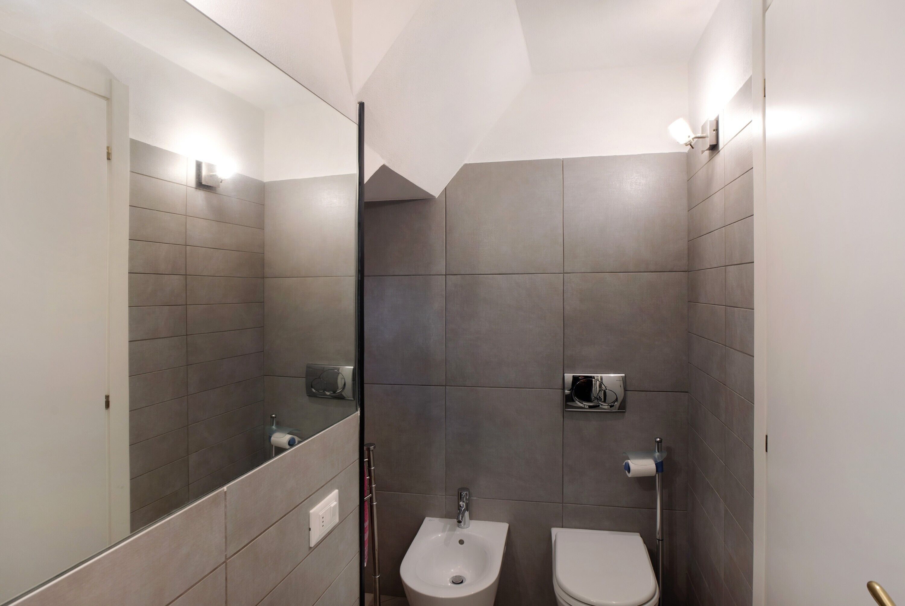 Een moderne badkamer met een bidet, toilet en een spiegel.