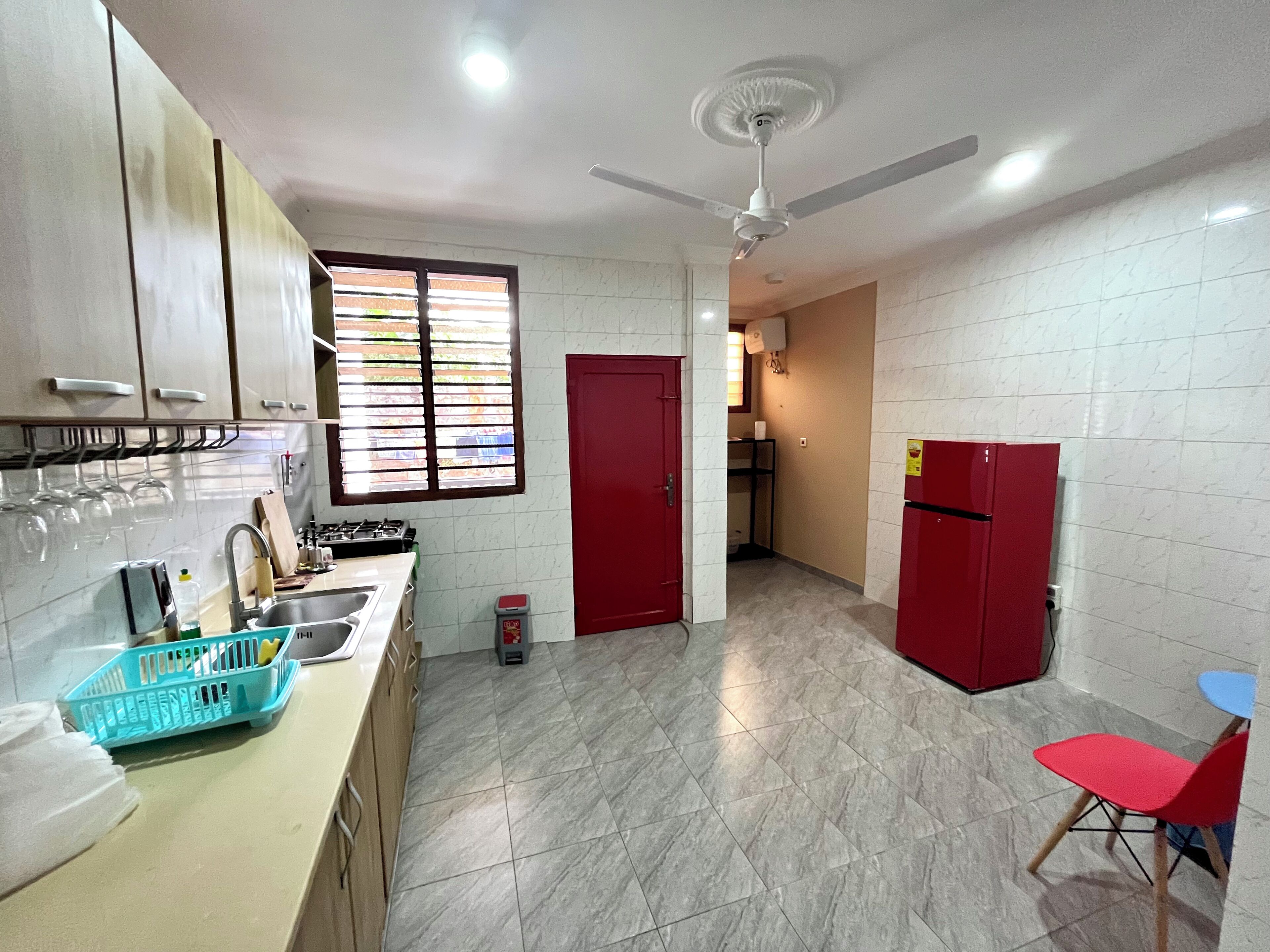 Una cocina con estufa a gas, lavamanos y un refrigerador rojo.