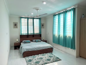 A bedroom with a bed, two bedside tables, a ceiling fan, and a wardrobe.