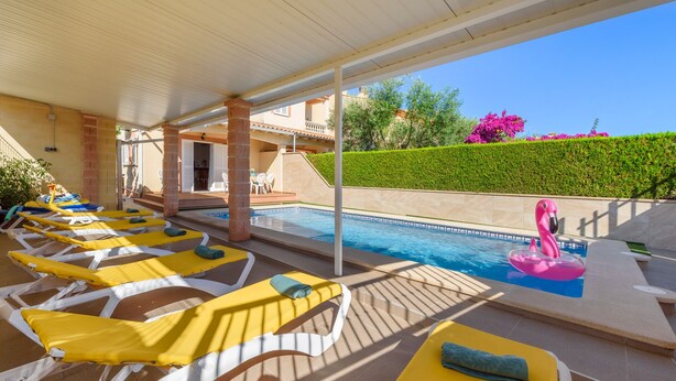 Zona de piscina con tumbonas, una piscina y un flotador con forma de flamenco rosa.