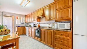 Una cocina con armarios de madera, microondas, horno y lavaplatos.