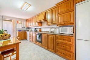 Een keuken met houten kastjes, een magnetron, een oven en een spoelbak.