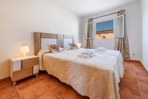 A hotel room with a bed, nightstand, lamp, and a window with curtains.
